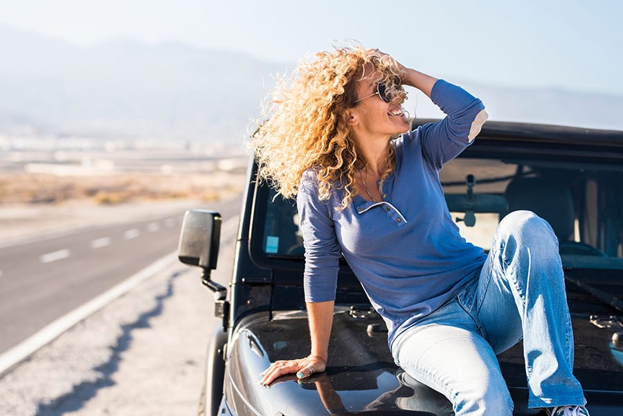 Mature-Blonde-lady-wearing-tinted-Jeep-Multifocal-precription-spectacles-sitting-on-the-bonnet-of-her-4x4-1.jpg